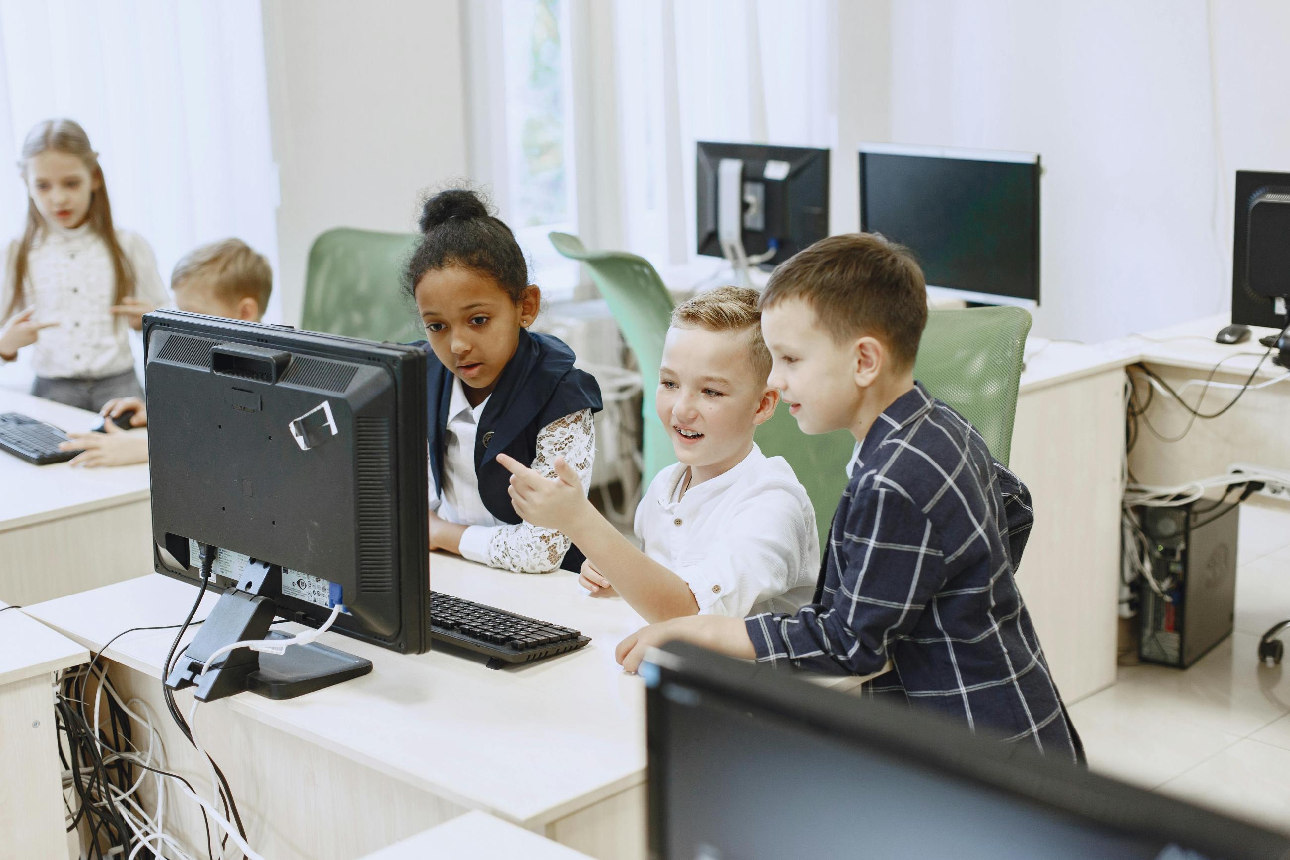 Children in a classroom looking at a computer